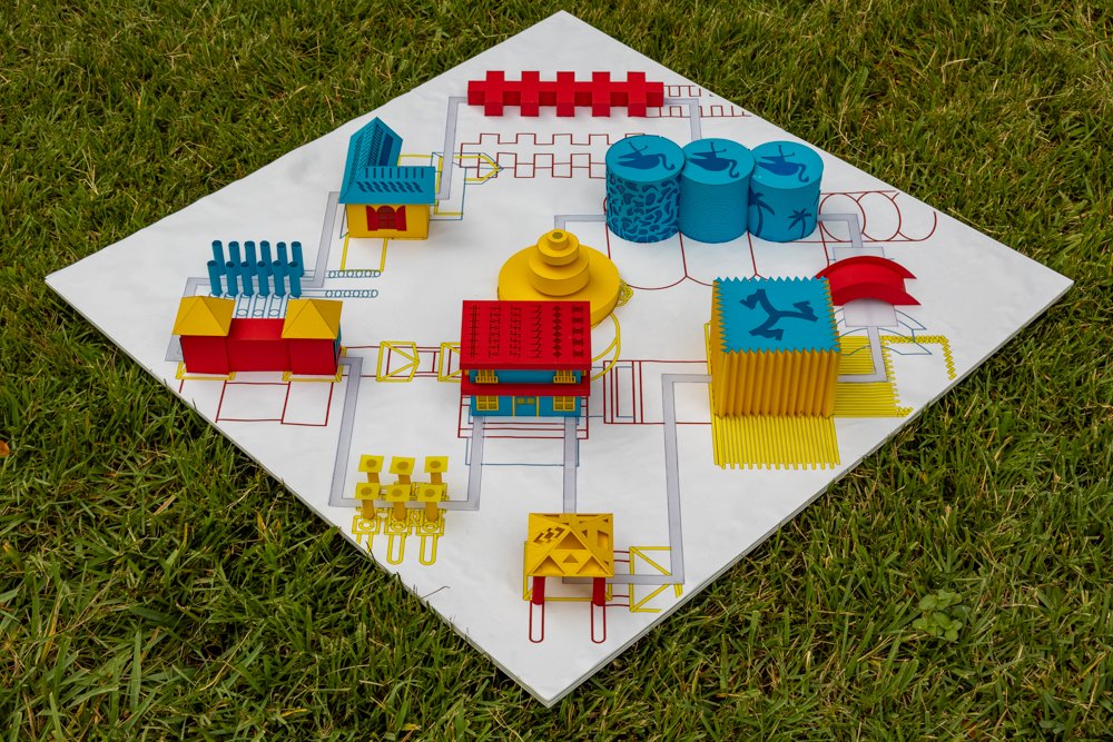 Section 7 abstraction model from above on grass: red, yellow and blue buildings on a white base